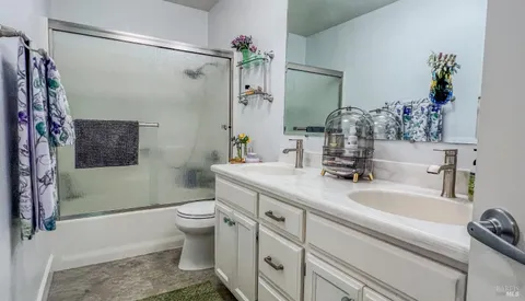 a bathroom with a granite countertop sink a toilet a shower and a mirror