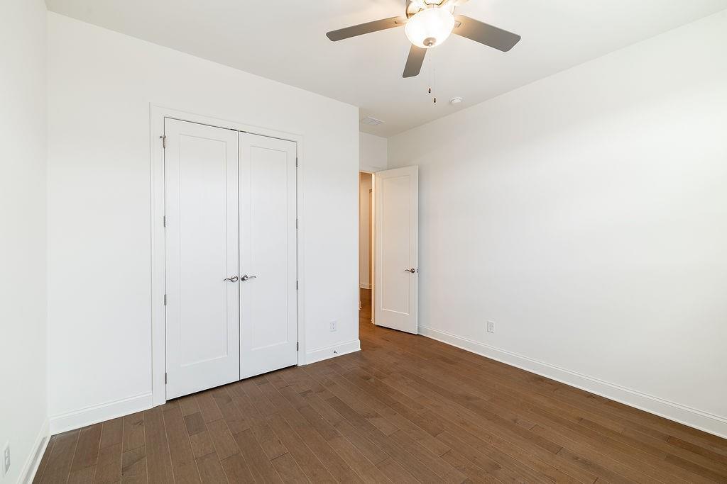 6954 Scenic Overlook Trace Flowery Branch, GA 30542 - Photo 11 of 55 an empty room with a ceiling fan and wooden floor