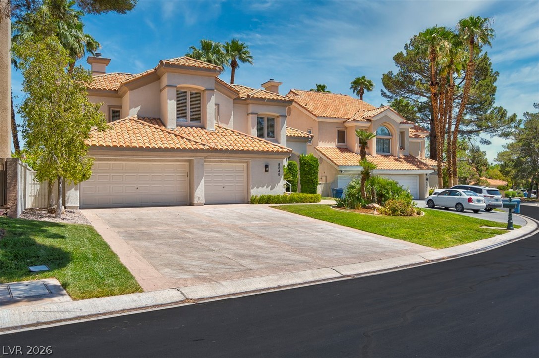 8848 Rainbow Ridge Drive Las Vegas, NV 89117 - Photo 1 of 43 A terracotta-tiled roof crowns this stucco-finished home, featuring multiple garages and lush green landscaping.