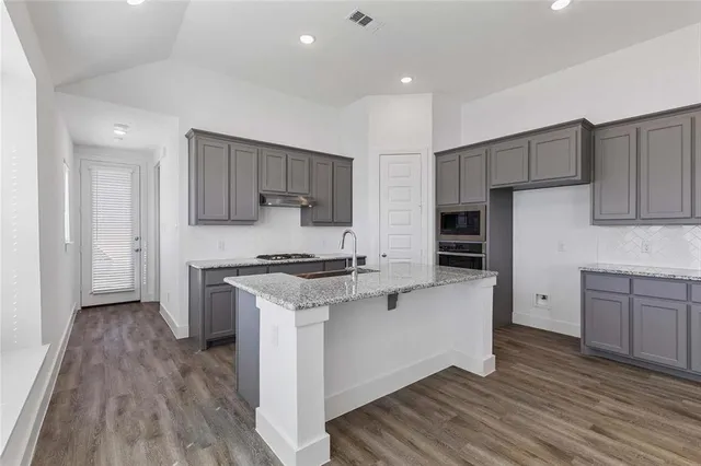 a kitchen with stainless steel appliances a stove top oven a sink and a refrigerator