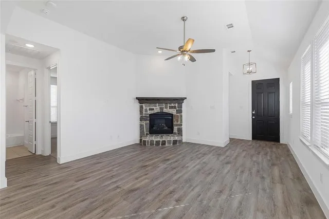 an empty room with wooden floor fireplace and windows