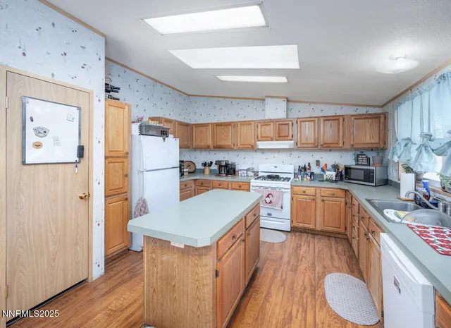 a kitchen with stainless steel appliances granite countertop a refrigerator a sink dishwasher a stove and a dining table with wooden floor