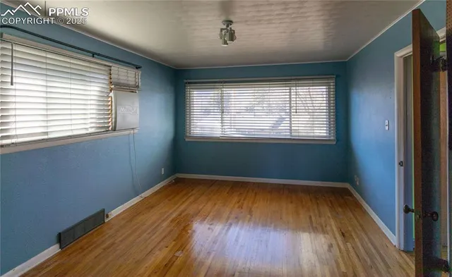 a view of an empty room with wooden floor and a window