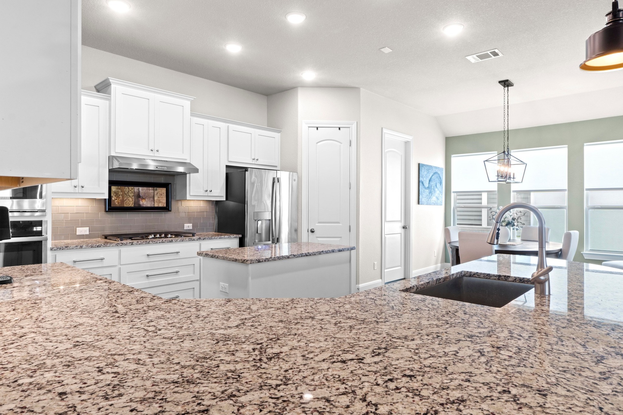 1329 Siena Sunset Road Leander, TX 78641 - Photo 12 of 33 a kitchen with stainless steel appliances kitchen island granite countertop a refrigerator a stove a sink and a sink with wooden floor