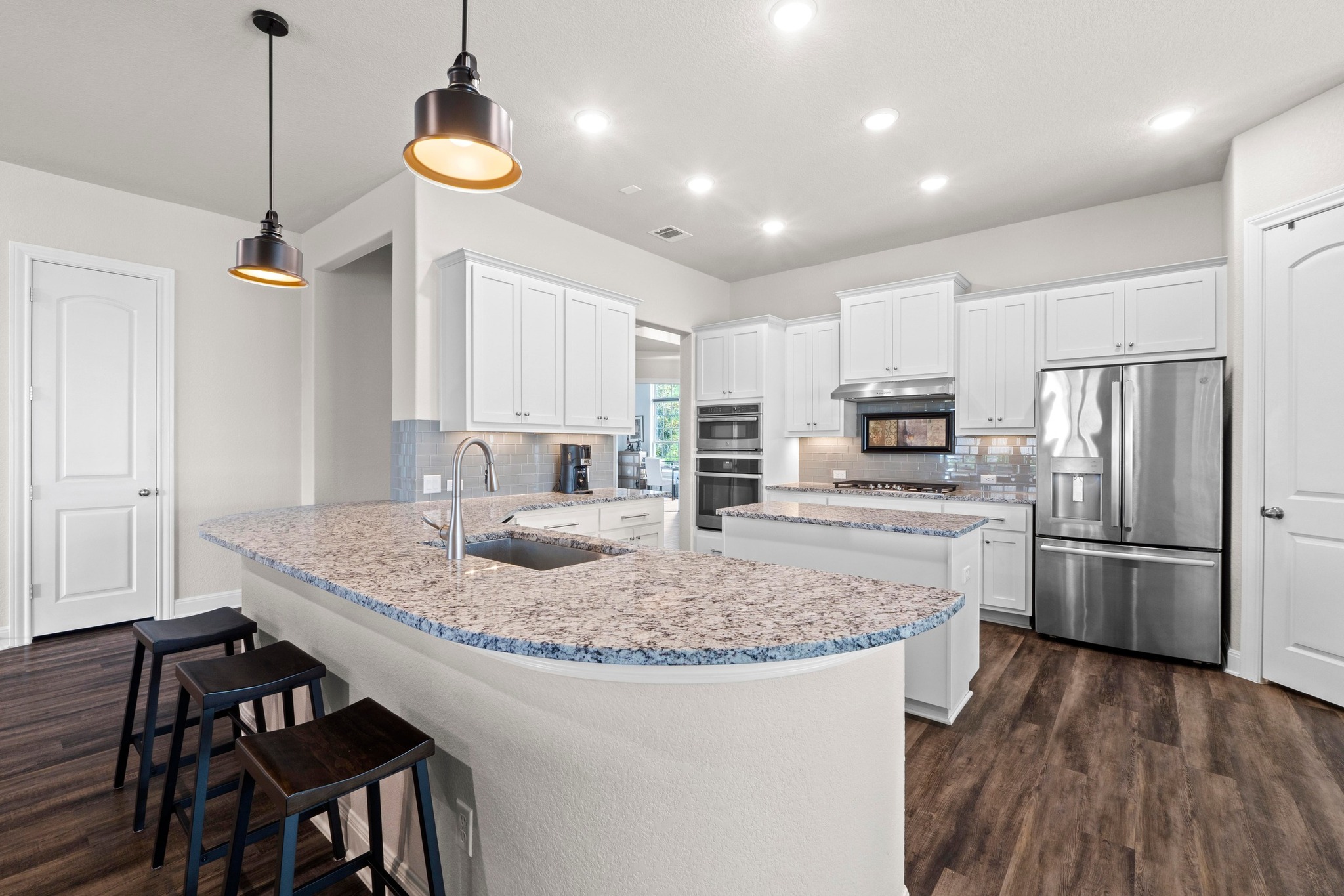1329 Siena Sunset Road Leander, TX 78641 - Photo 9 of 33 a kitchen with kitchen island white cabinets and stainless steel appliances