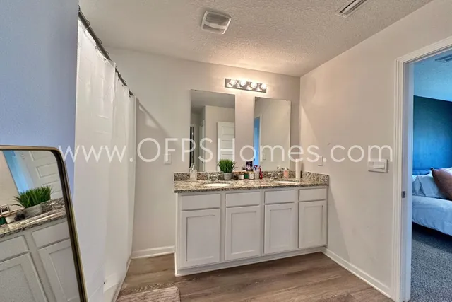 a spacious bathroom with a double vanity sink a mirror and a shower