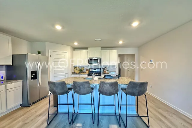 a view of kitchen with refrigerator stove dining table and chairs