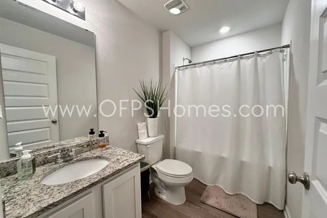 a bathroom with a granite countertop sink toilet and shower