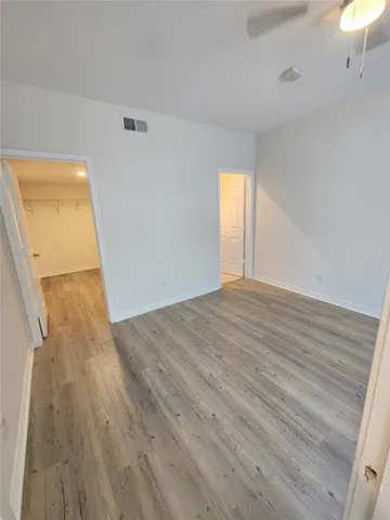 a view of empty room with wooden floor and fan