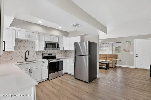a kitchen with stainless steel appliances a refrigerator sink and microwave