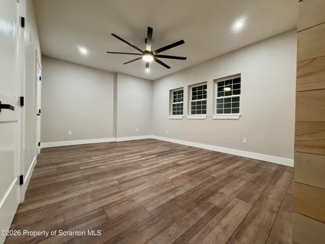 a view of empty room with wooden floor and fan