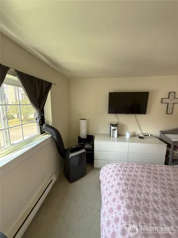 a bedroom with a bed and a flat tv screen on dresser
