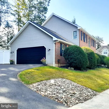 a view of a house with a yard plants and large tree