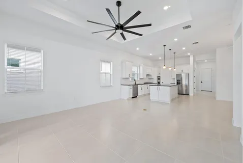 an empty room with windows and ceiling fan