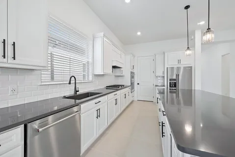 a kitchen with granite countertop a sink stove and cabinets