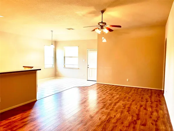 a view of a room with wooden floor a ceiling fan and windows