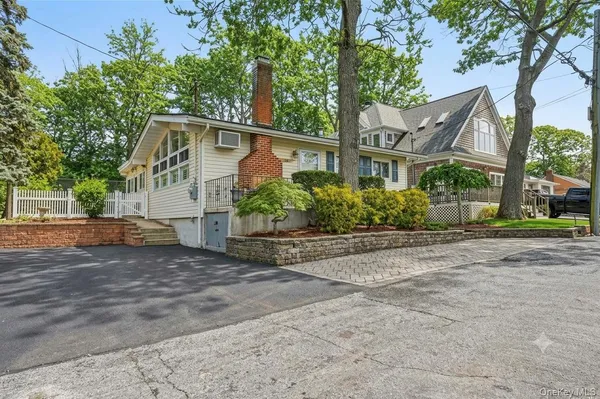 a view of a house with a small yard plants and a large tree