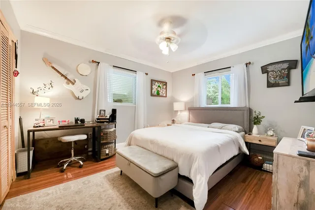 a bedroom with a bed a desk and chair with wooden floor