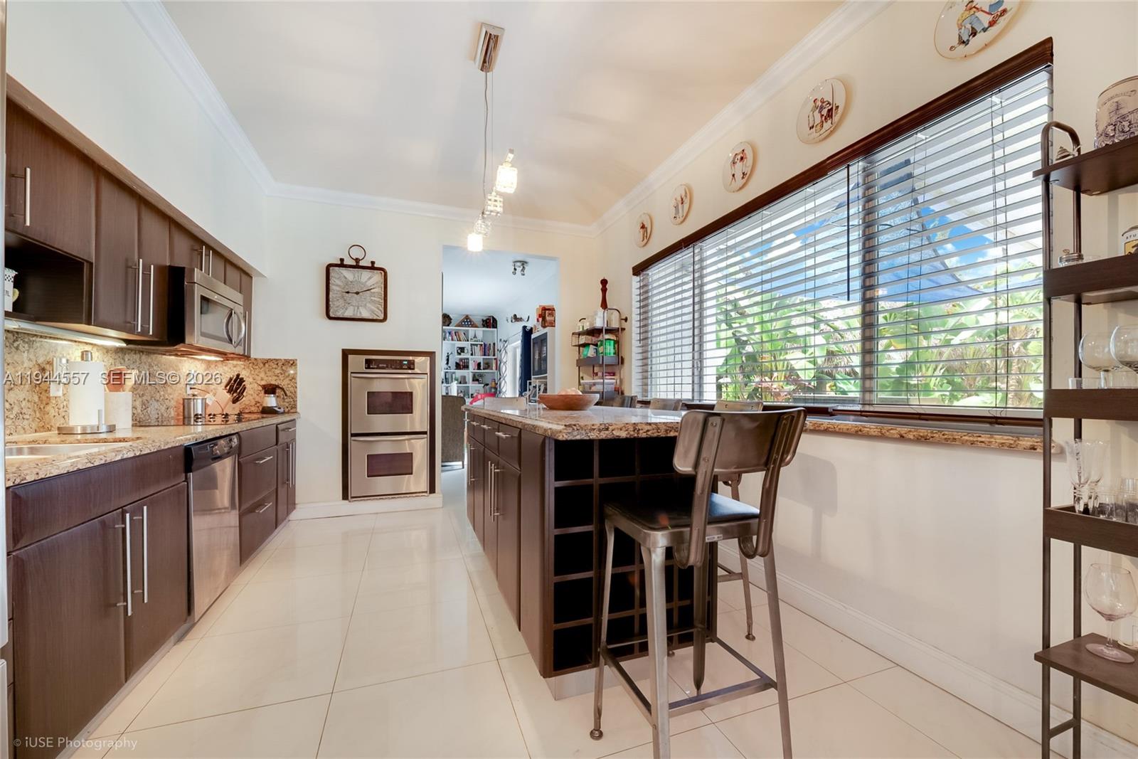 8265 Southwest 119th Street Miami, FL 33156 - Photo 14 of 34 a kitchen with kitchen island granite countertop wooden cabinets and stainless steel appliances