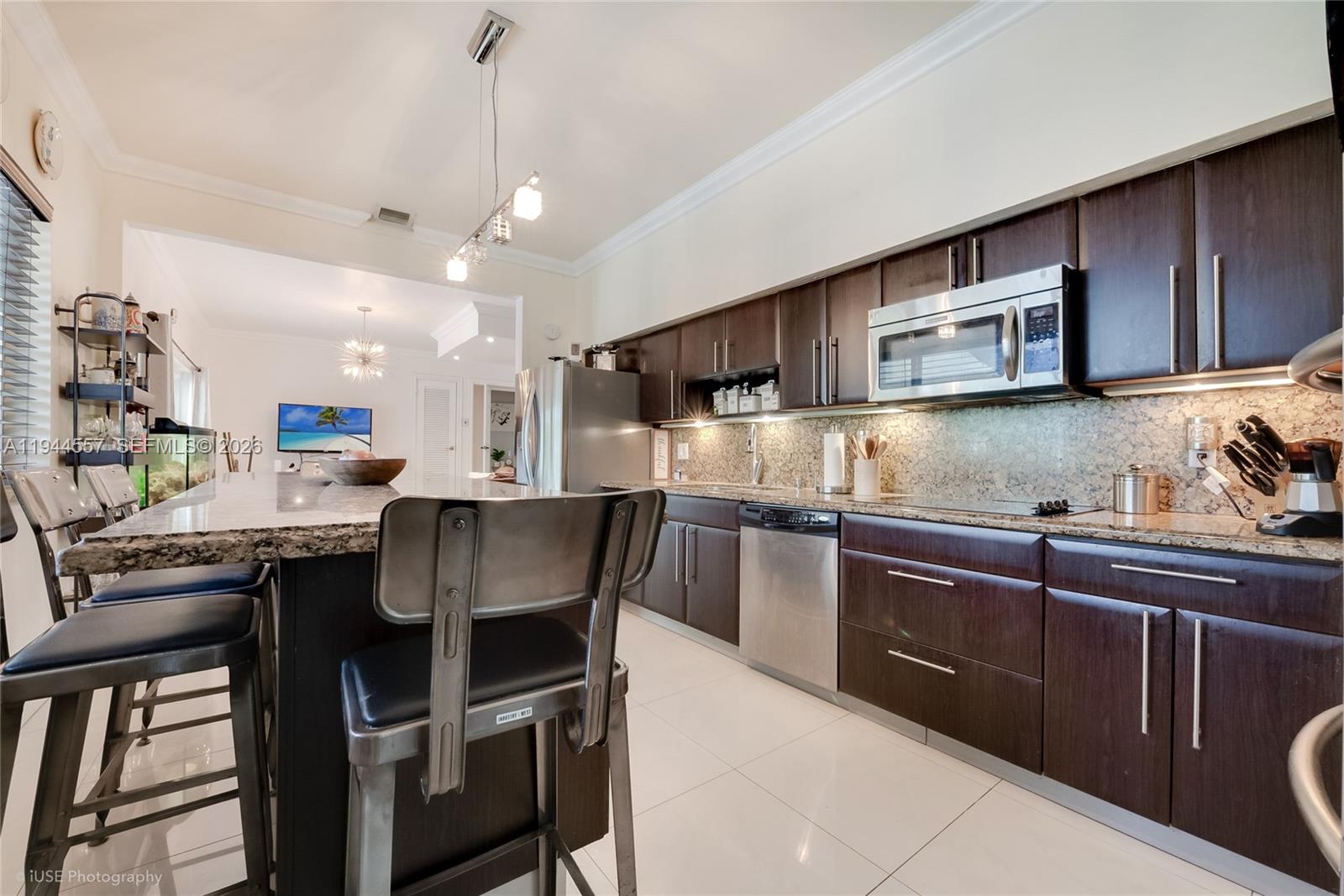 8265 Southwest 119th Street Miami, FL 33156 - Photo 15 of 34 a kitchen with stainless steel appliances granite countertop wooden cabinets a stove top oven a sink and dishwasher