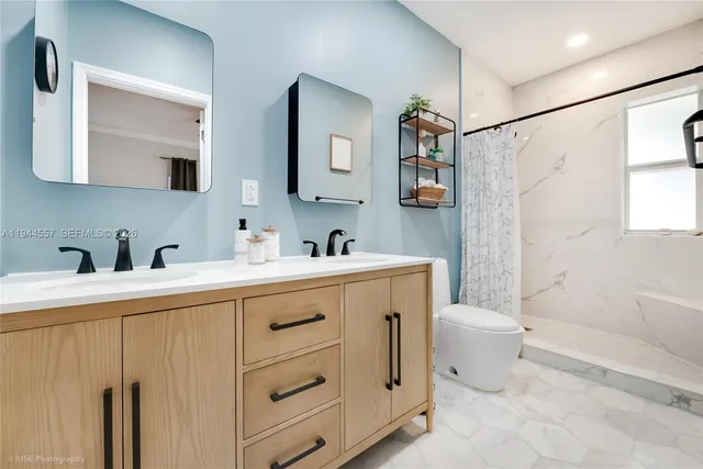 a spacious bathroom with a double vanity sink a mirror a toilet and a bathtub