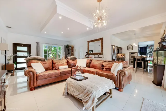 a living room with furniture a chandelier and a flat screen tv