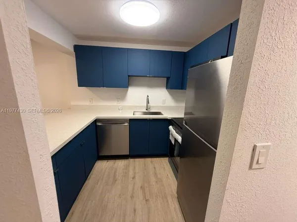 a kitchen with a sink a refrigerator and wooden floor