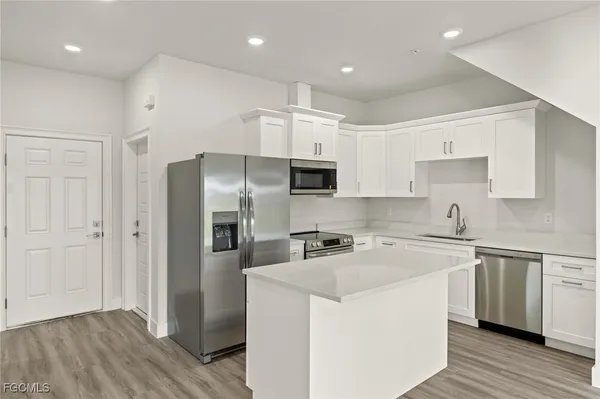 a kitchen with granite countertop a refrigerator and a stove top oven