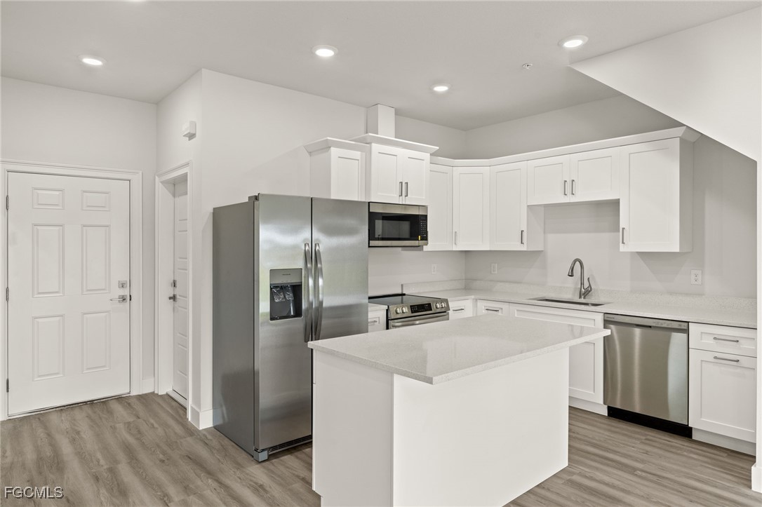 14985 Sunset Eve Loop Fort Myers, FL 33919 - Photo 5 of 18 a kitchen with stainless steel appliances granite countertop a refrigerator a sink dishwasher a stove and white countertops with wooden floor