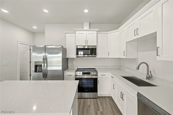 a kitchen with stainless steel appliances a stove a microwave and white cabinets