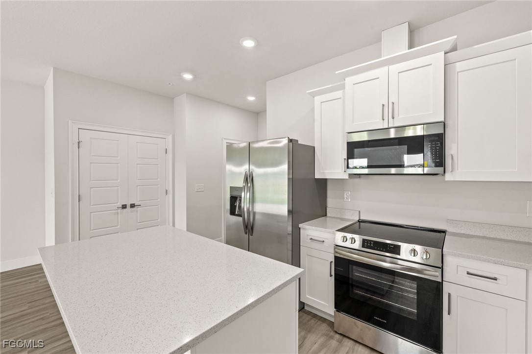 14985 Sunset Eve Loop Fort Myers, FL 33919 - Photo 7 of 18 a kitchen with stainless steel appliances a stove a microwave and white cabinets
