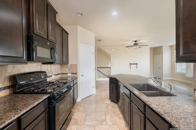 a kitchen with granite countertop stainless steel appliances a sink stove and cabinets