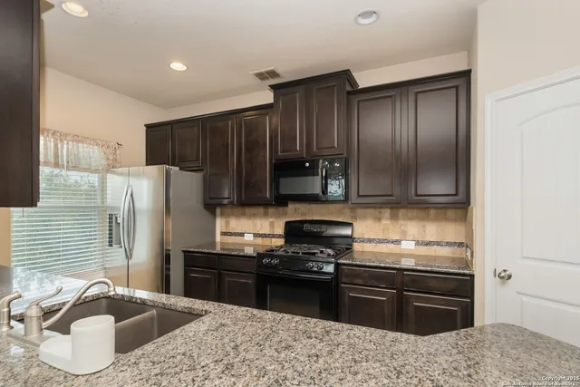 a kitchen with granite countertop a sink cabinets and stainless steel appliances