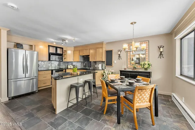 a kitchen with a refrigerator a stove a sink a dining table and chairs