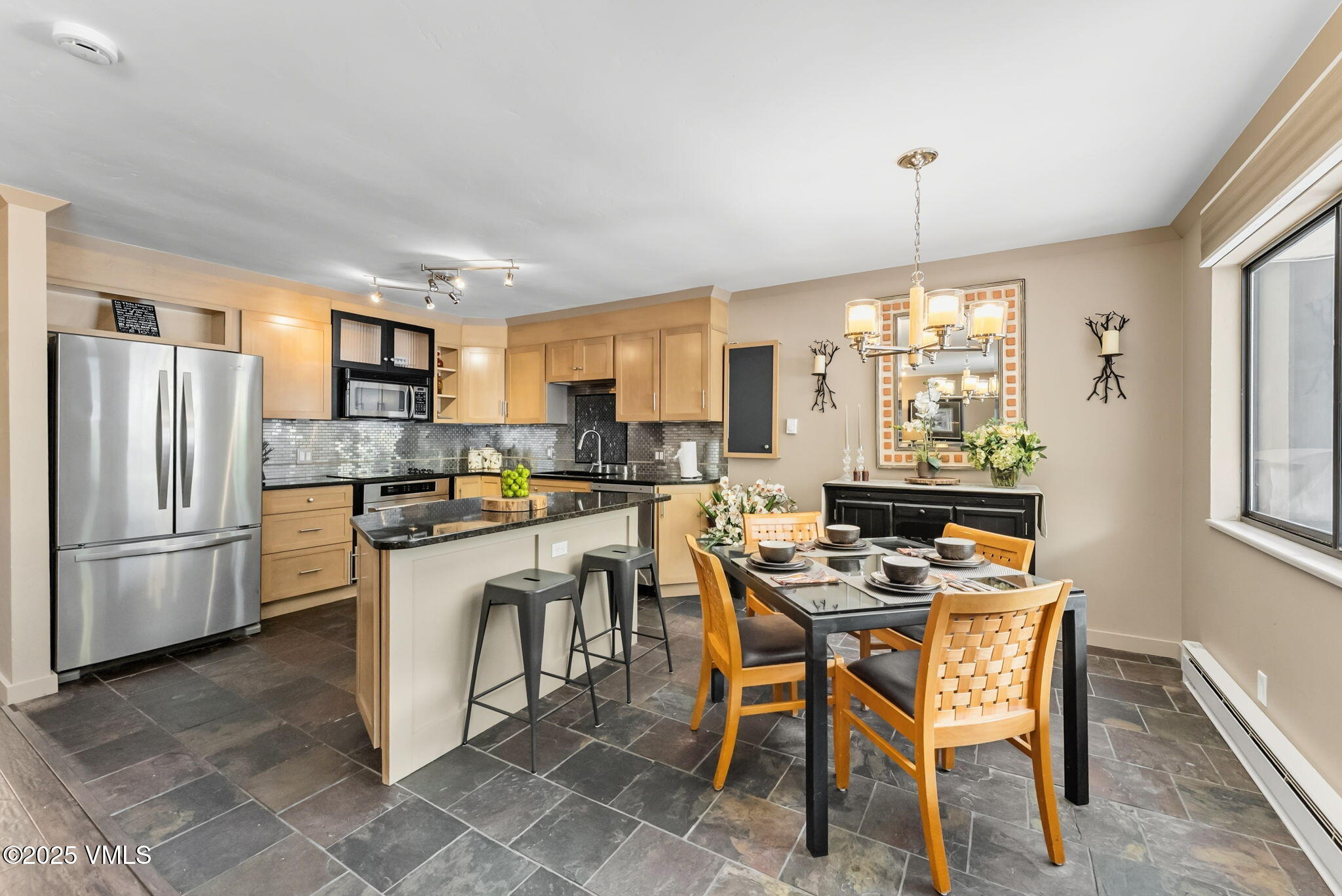 a kitchen with a refrigerator a stove a sink a dining table and chairs