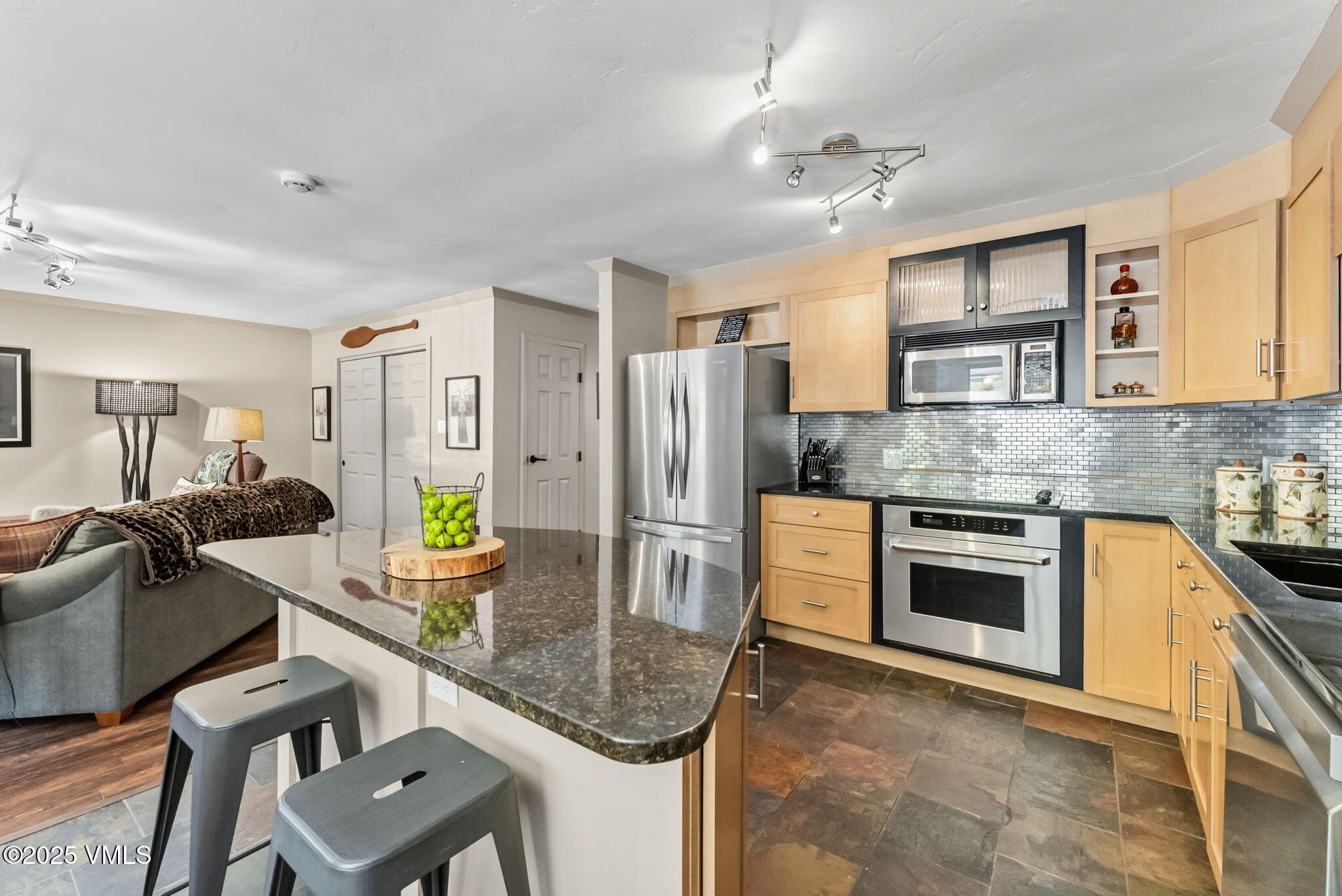 596 Daisy Lane, Unit 10 Avon, CO 81620 - Photo 4 of 34 a kitchen with stainless steel appliances granite countertop a stove top oven a refrigerator a sink a dining table and chairs with wooden floor