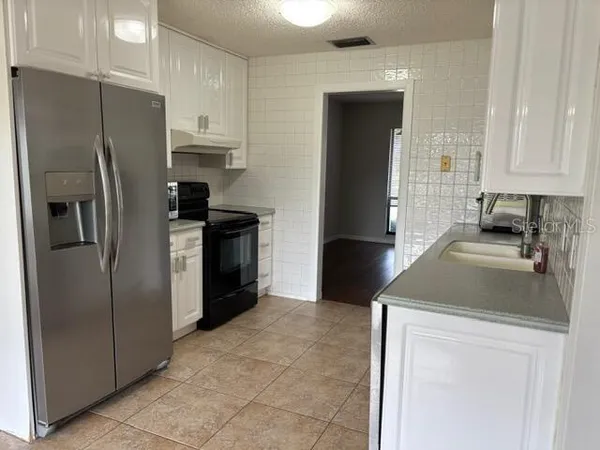 a kitchen with stainless steel appliances granite countertop a sink and a refrigerator