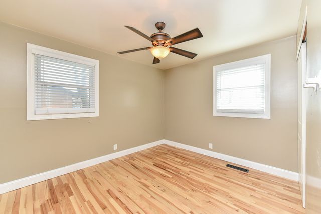 a view of a room with wooden floor and a ceiling fan