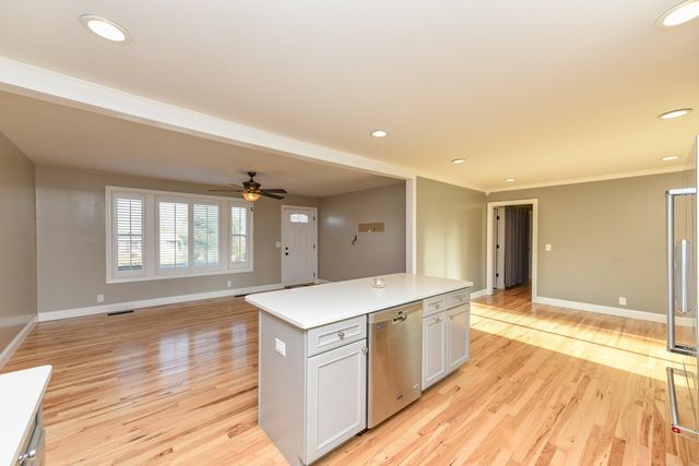 a large white kitchen with wooden floor and a sink