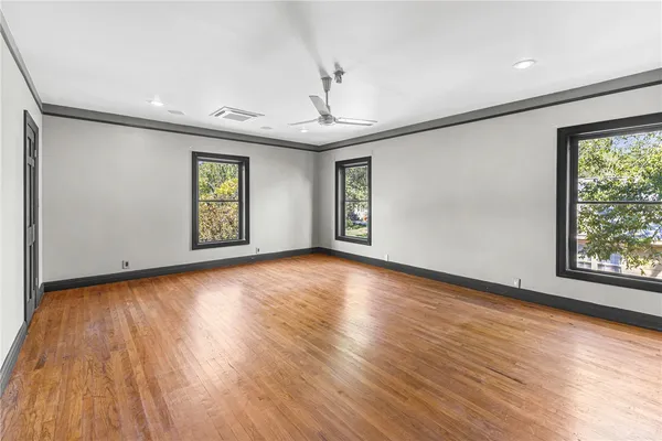 an empty room with wooden floor and windows