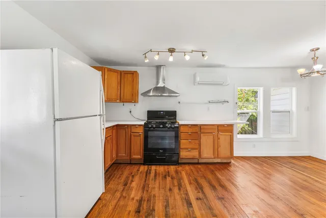 a kitchen with granite countertop wooden floors stainless steel appliances and a window