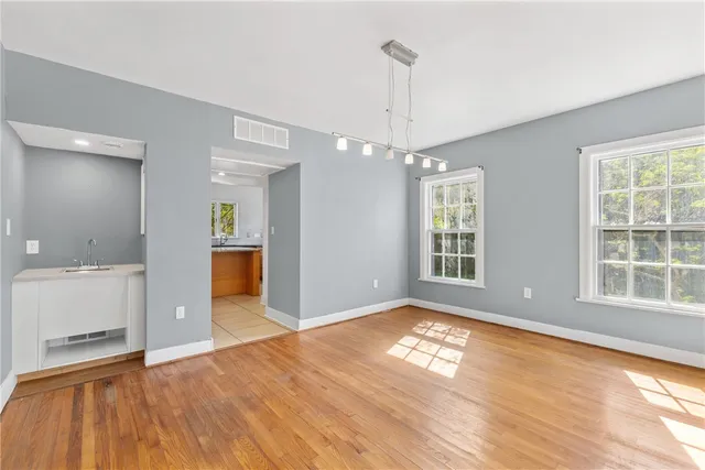 a view of an empty room with window and wooden floor