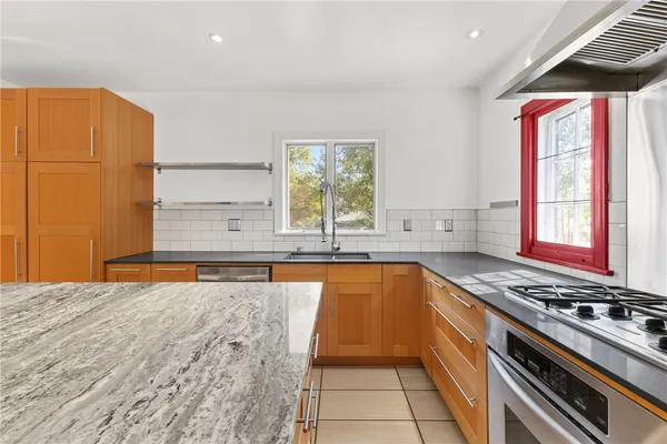 a kitchen with stainless steel appliances granite countertop a stove a sink and a microwave