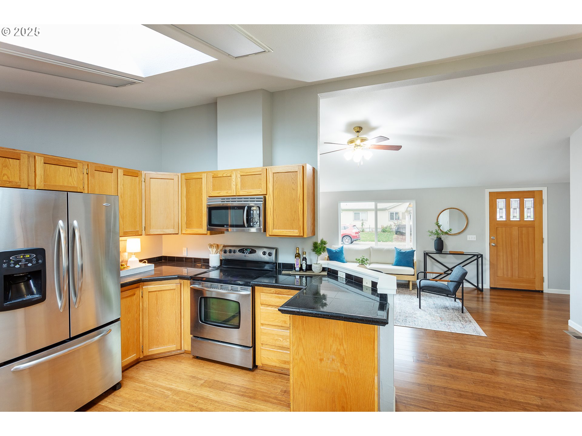2655 Atticus Way Eugene, OR 97404 - Photo 9 of 27 a kitchen with stainless steel appliances granite countertop a stove top oven a refrigerator a sink dishwasher and a dining table with wooden floor