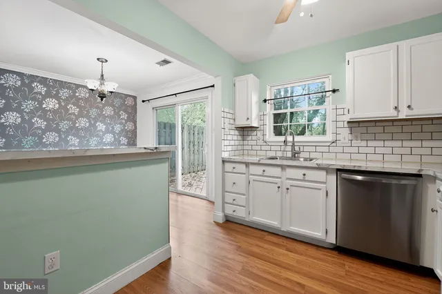 a kitchen with stainless steel appliances granite countertop a sink cabinets and wooden floor