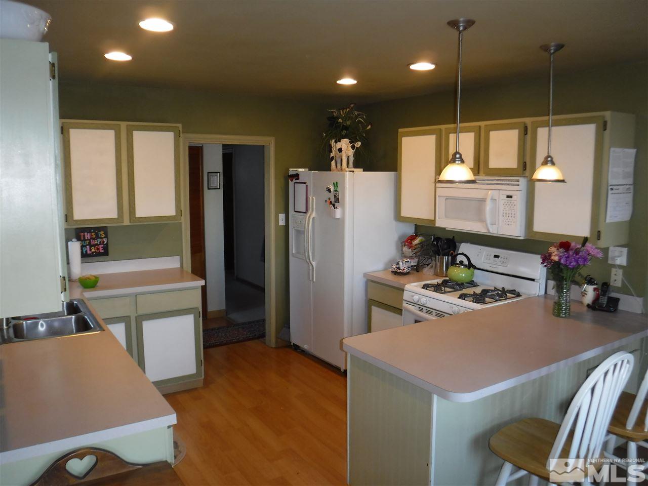 2015 Ives Avenue Reno, NV 89503 - Photo 7 of 21 a kitchen with a refrigerator a stove and a dining table with wooden floor