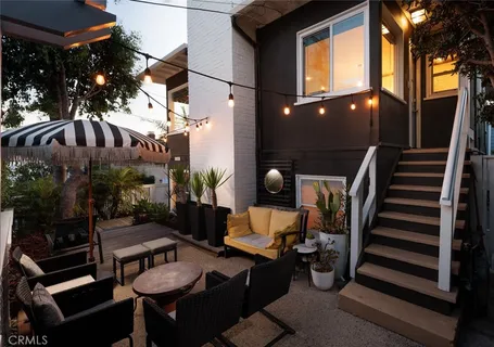 a backyard of a house with couches table and chairs and potted plants