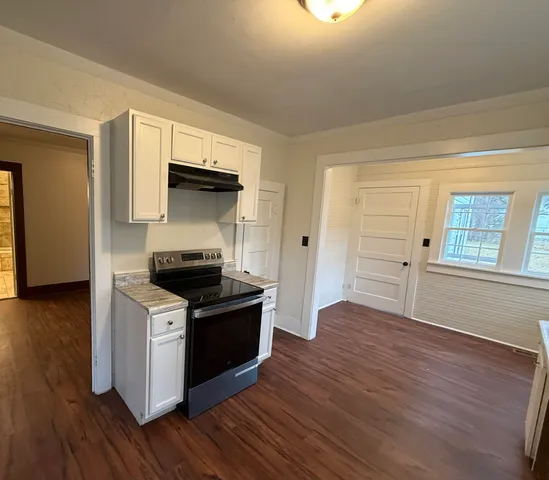 a kitchen with granite countertop a stove and a wooden floor