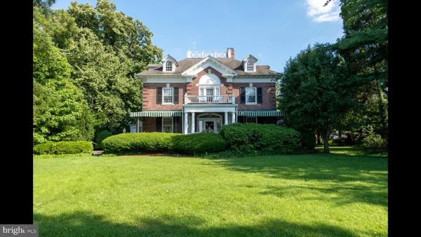 a view of a big yard in front of a brick house with large windows