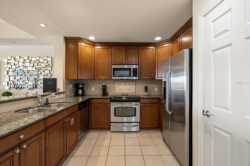 1114 Sunset View Circle, Unit 402 Reunion, FL 34747 - Photo 6 of 32 a kitchen with stainless steel appliances granite countertop a stove a sink and a refrigerator